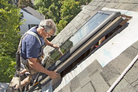 Man positioning skylight on roof