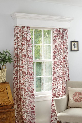 A window cornice with white curtains hanging from it. The curtains have a red floral pattern.