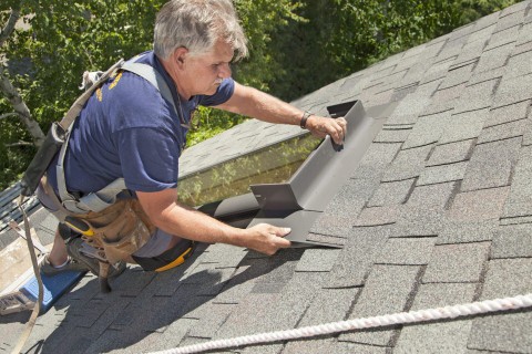 Man installs saddle flashing on skylight