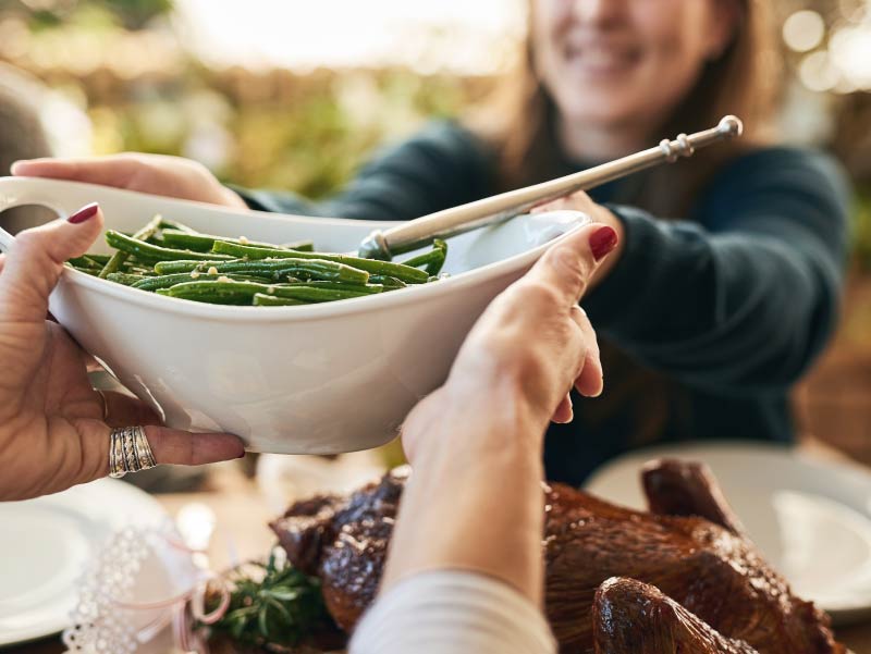 Diners passing bowl of green beans