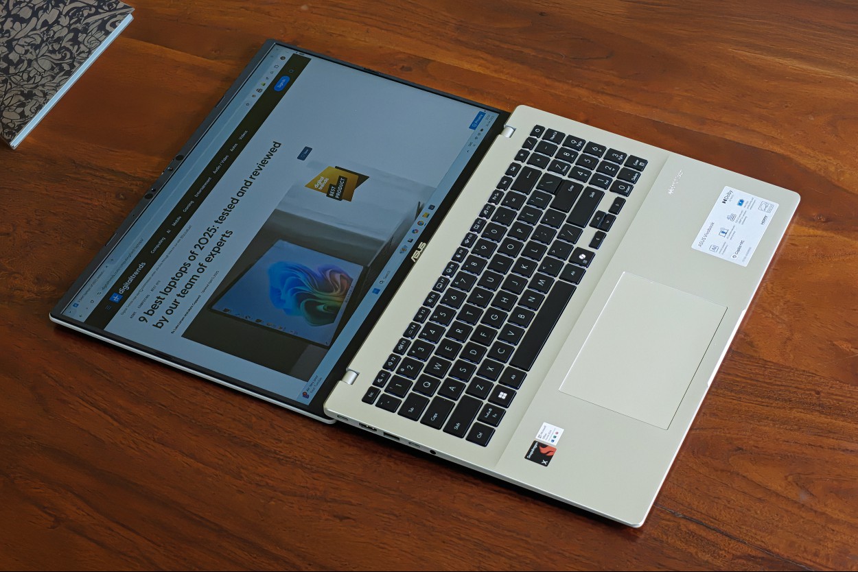 Display on the Asus Vivobook 16 X1607QA Copilot+ PC laptop with Qualcomm Snapdragon X ARM 64 chip lays out 180-degrees on a wooden surface.