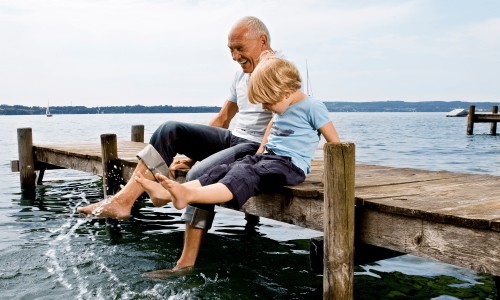 Father and son playing with water, splashing around on a dock