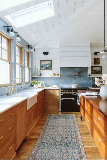 Kitchen with oak cabinets, marble countertops and blue subway tile backsplash