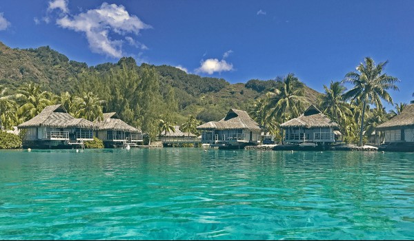 A photo of French Polynesian abodes on the water on a clear day.