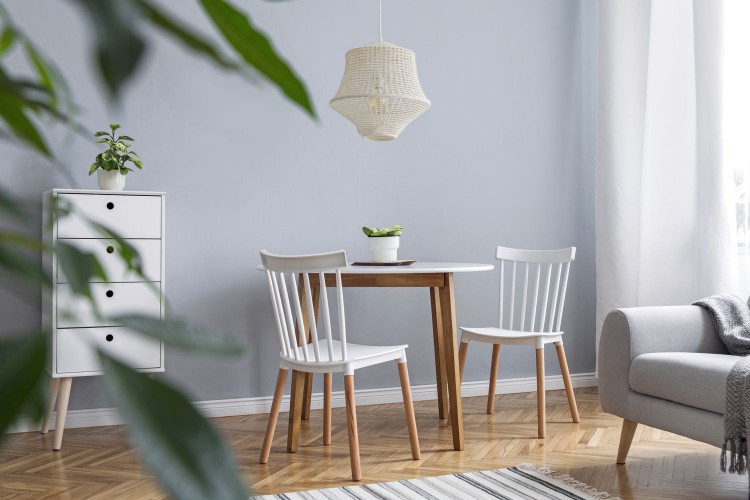 Modern scandinavian decor of living room with design furniture, family table, sofa and plants Brown wooden parquet and stylish carpet. Nice and minimalistic apartment.