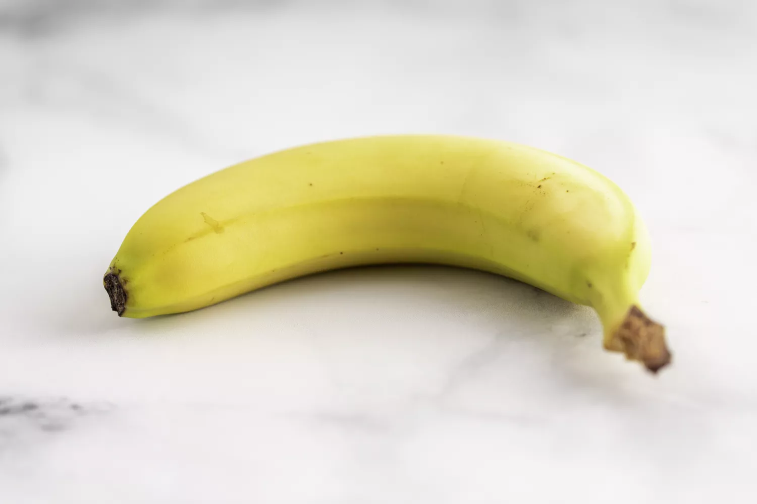 A single banana on a marble surface.