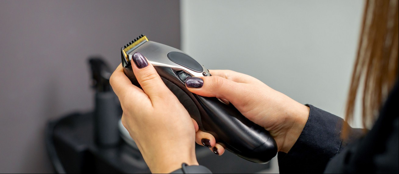 Electric clippers held by a woman.