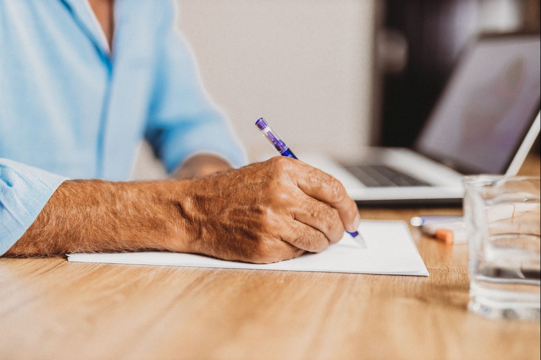 Man writing on a piece of paper on a table.