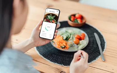 woman tracking calories with an app and eating lunch