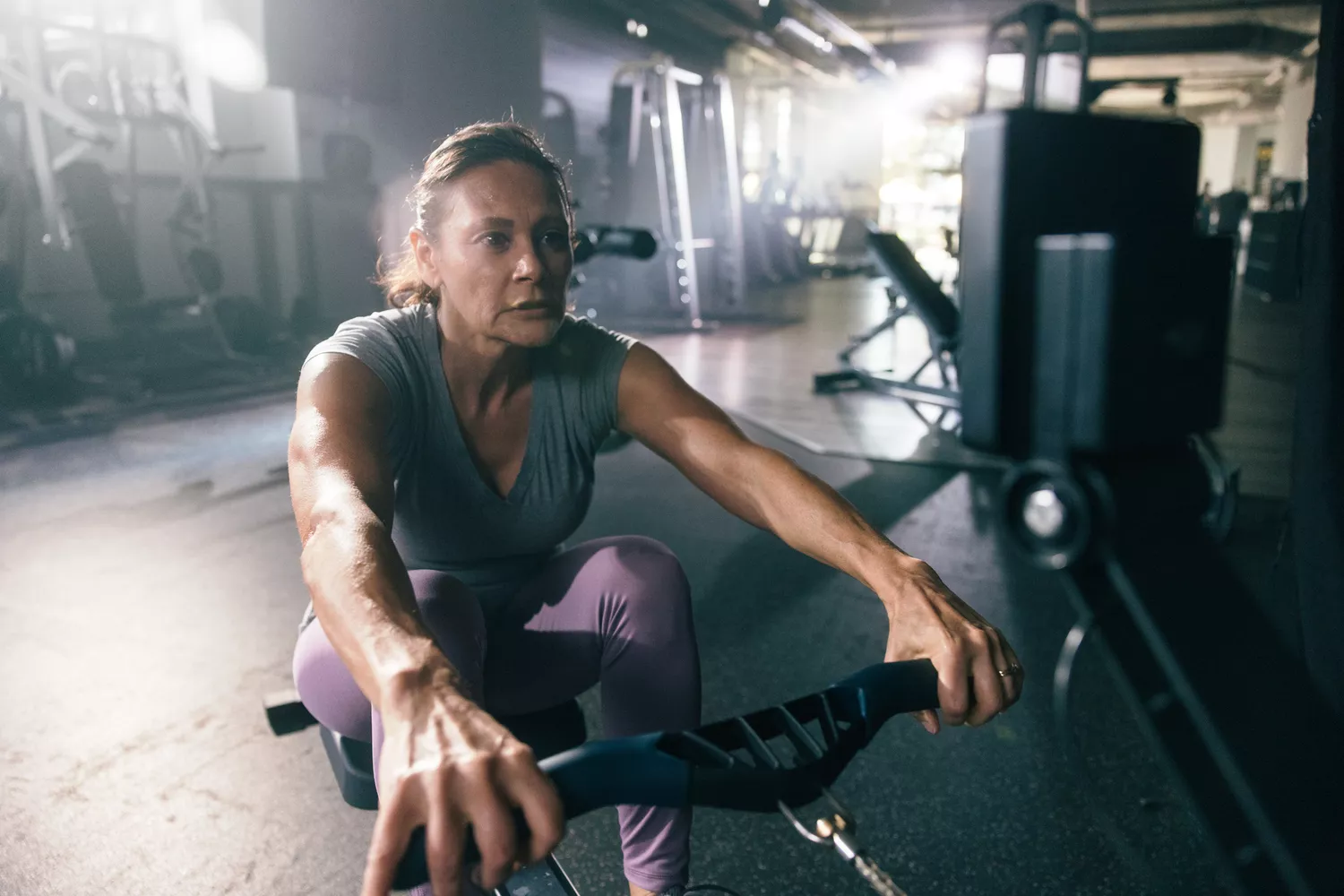 A woman uses a rowing machine at a gym in the morning.