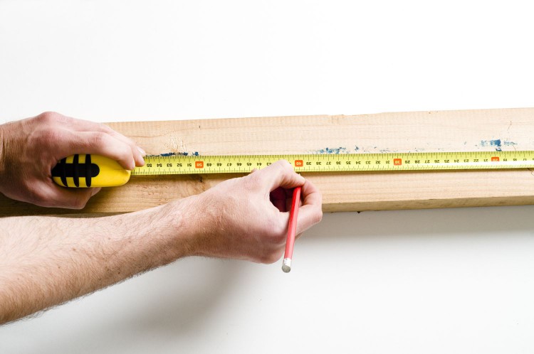 Hands measuring and marking wood