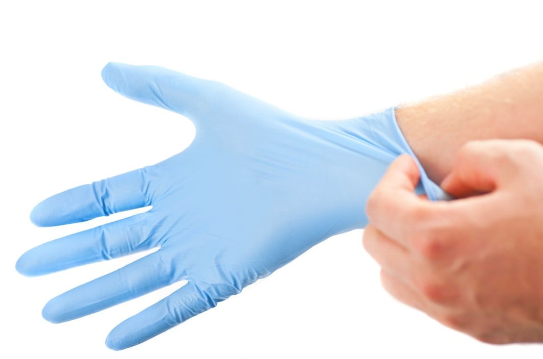 Blue exam glove being put onto a hand.