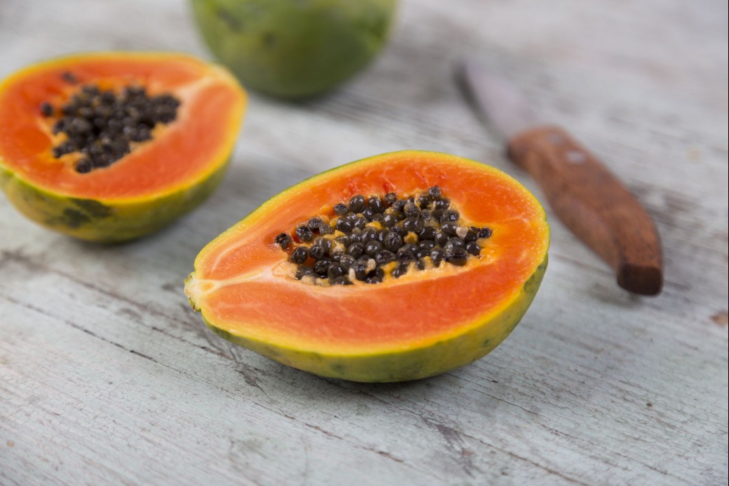 Papaya cut in half on a wood table.