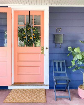 coral front door alongside blue siding 