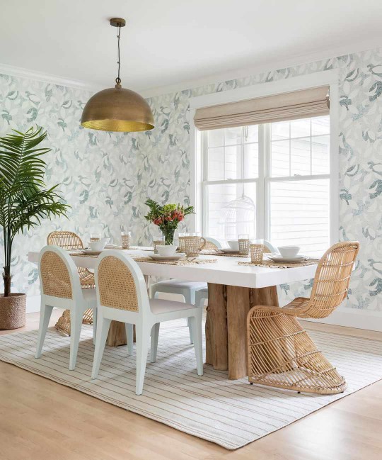 Whimsical dining room with blue wallpaper, cane backed dining chairs, and wicker S chairs 