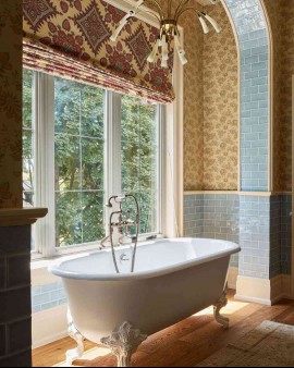 Bathroom with free standing tub, light blue subway tile, and yellow vintage wallpaper 