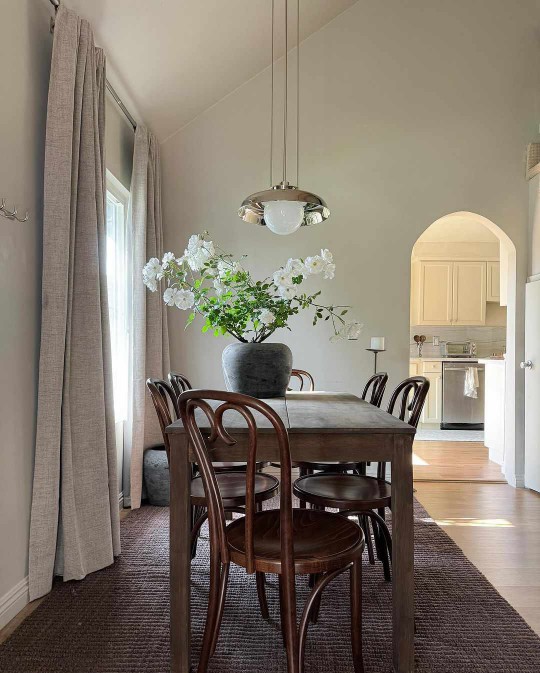 Dining room with rust farm table, industrial chrome pendant, and thonet style bentwood back cafe chairs