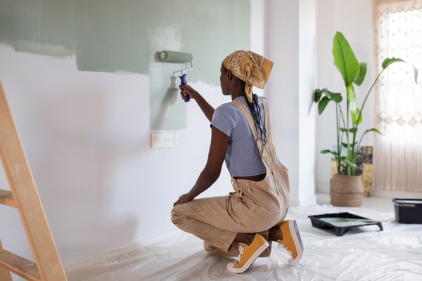 Female painting walls with a paint roller in an empty home