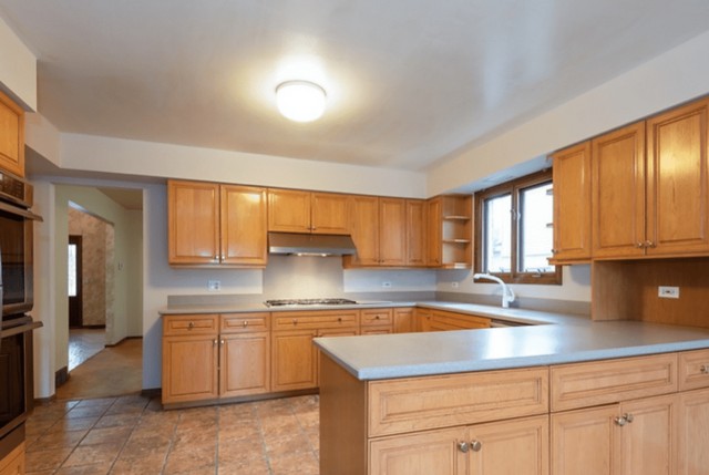 Boring oak kitchen with single ceiling light.