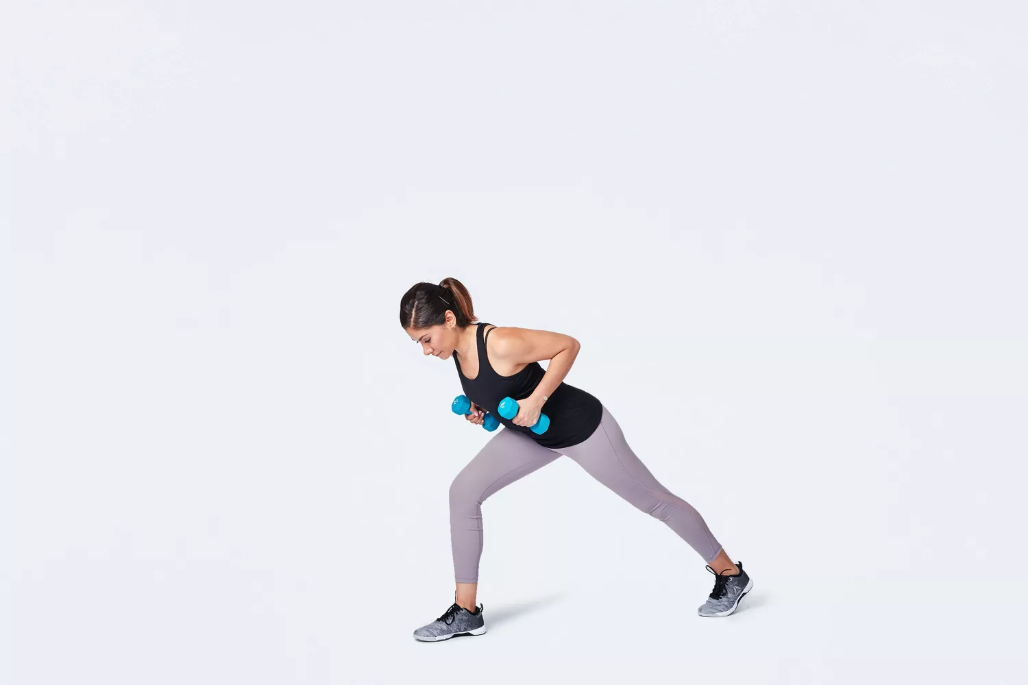 Woman in lunge position doing row exercise with dumbbells
