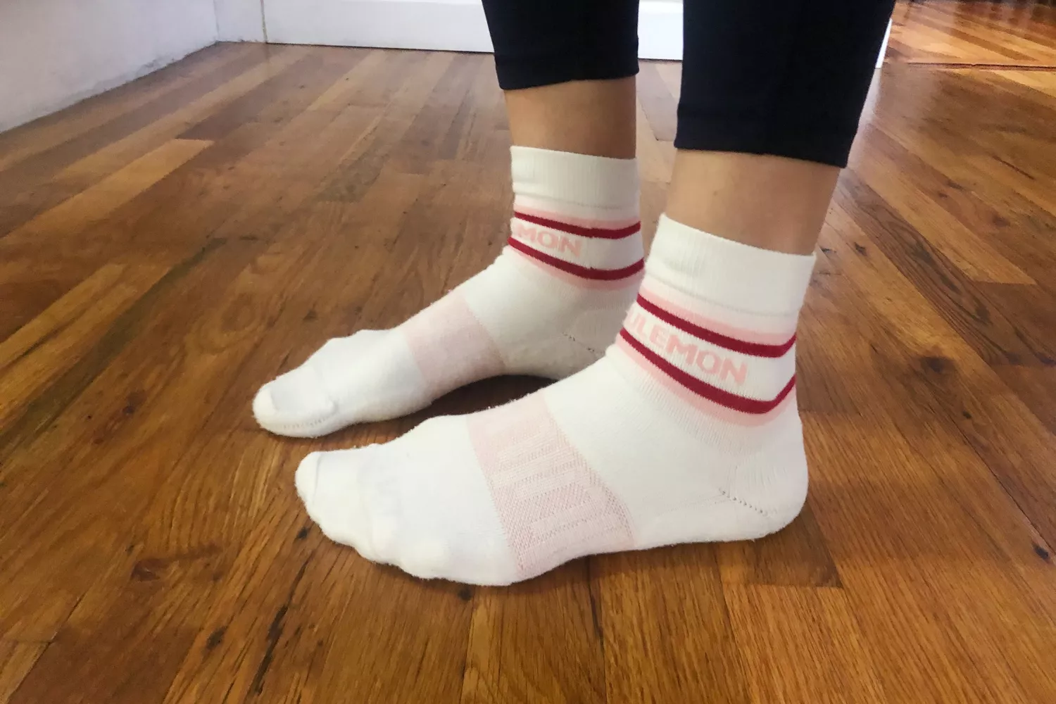 Feet wearing lululemon Daily Stride socks while standing on wood floor