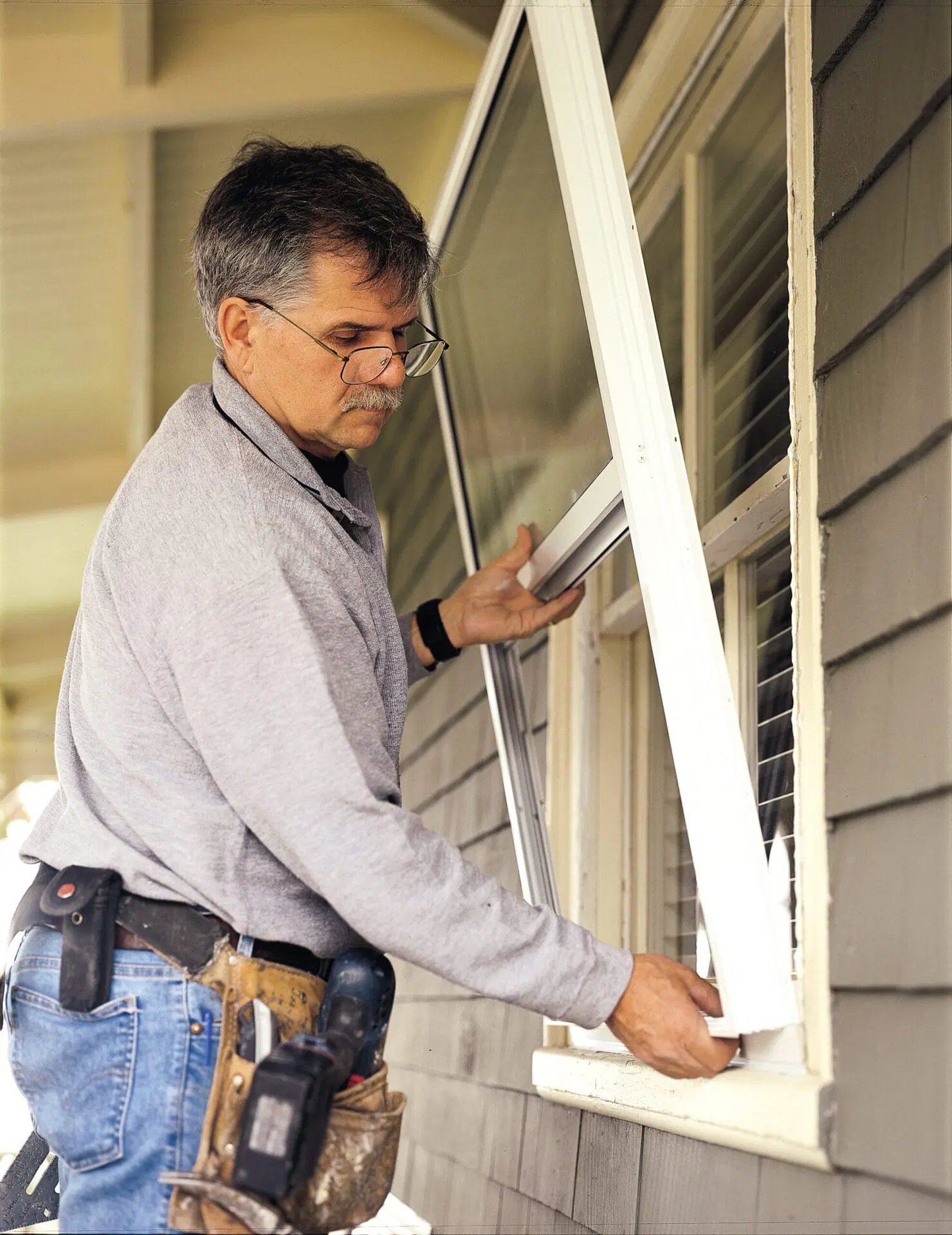 Image of Tom Silva installing storm windows on a home