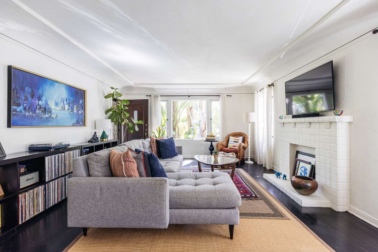 Gray sectional sofa in middle of long living room with white brisk fireplace