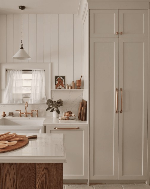 A white-filled kitchen with a small window lined with blinds and curtains