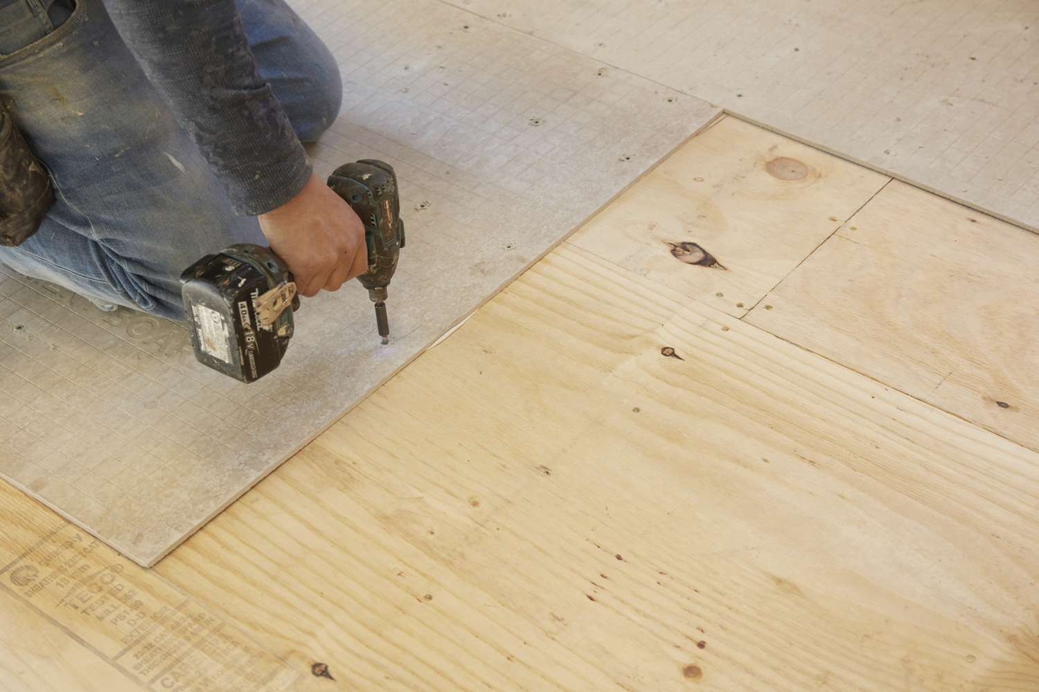 Cement backer boards screwed into plywood floor by hand