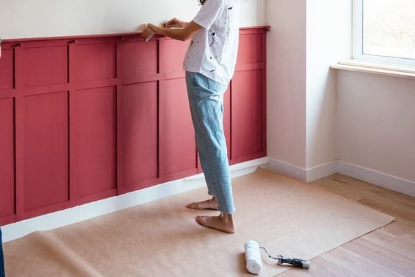 Woman installing faux panelling on a wall
