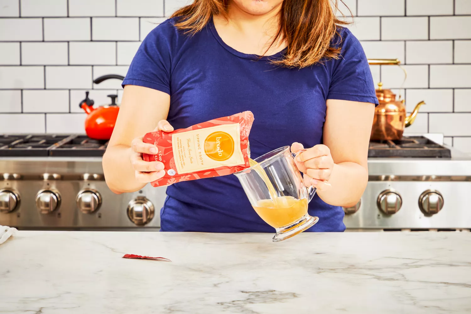 A person pours Brodo Hearth Bone Broth into a glass