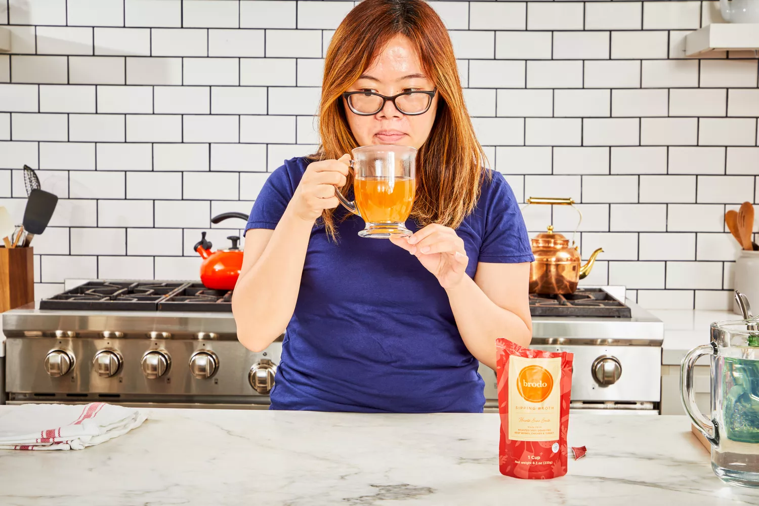 A person smells a glass of Brodo Hearth Bone Broth