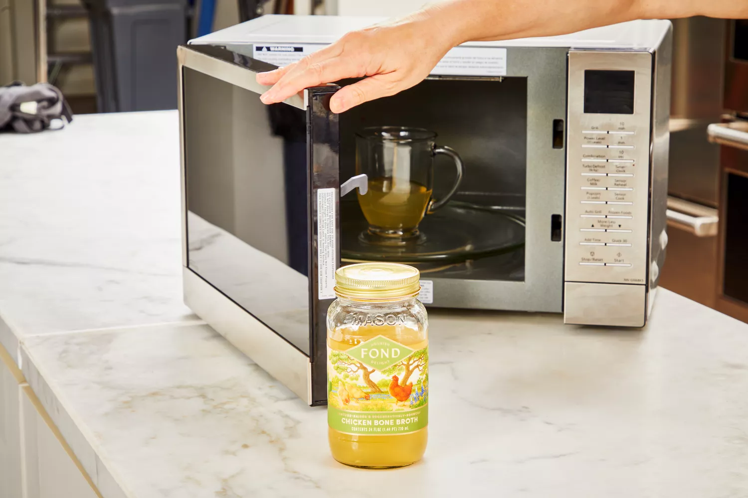 A person microwaves a glass of FOND Certified Organic Chicken Bone Broth