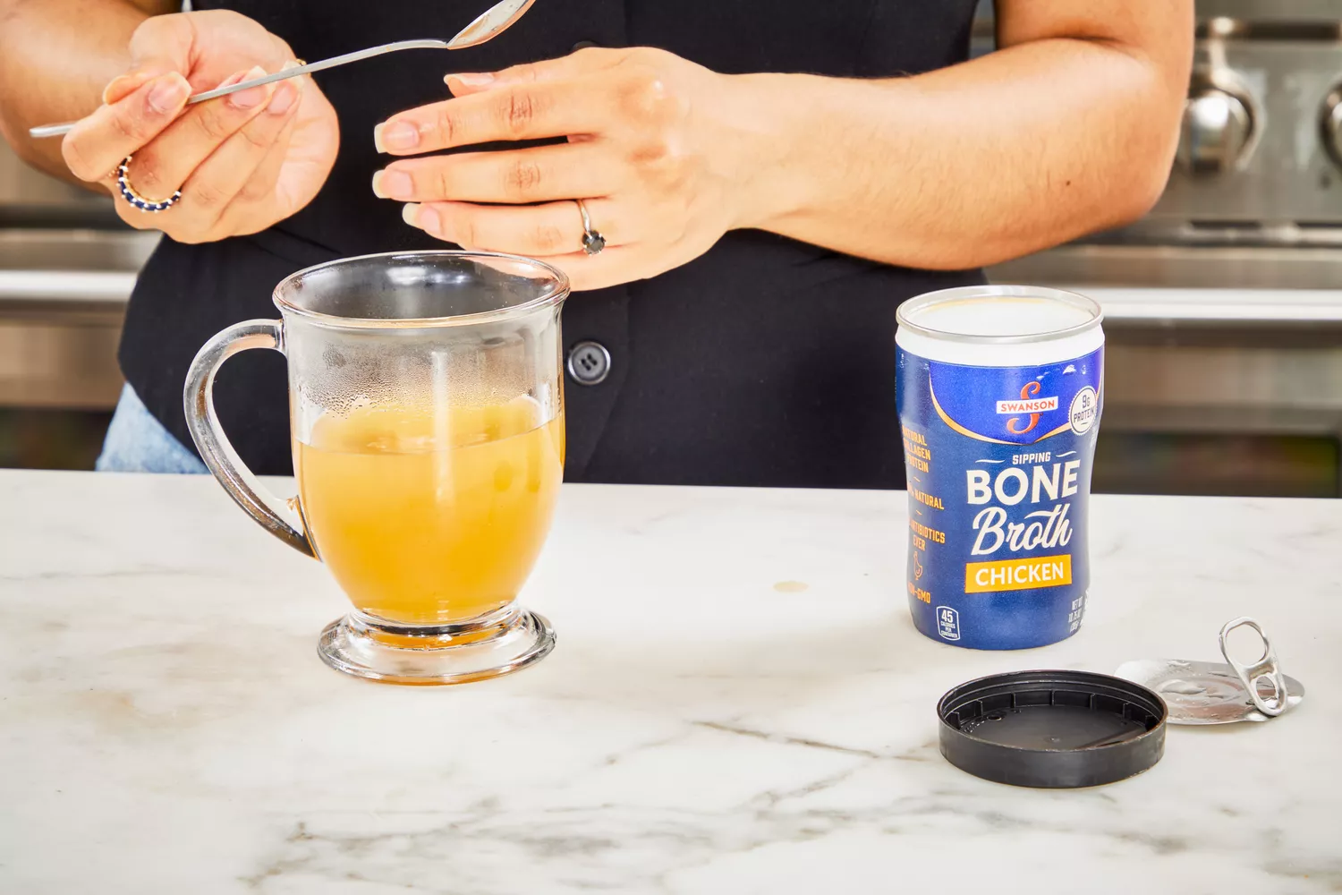 A person stirs Swanson Sipping Chicken Bone Broth in a glass