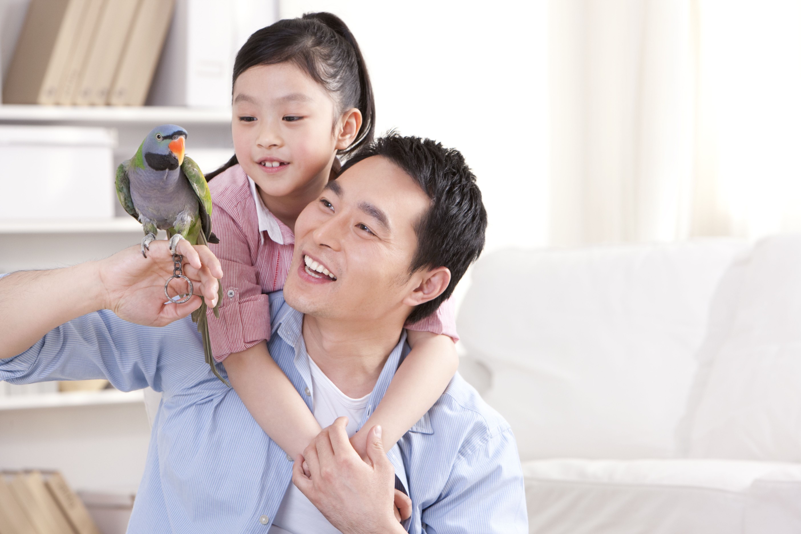 Father and daughter playing with a pet parrot