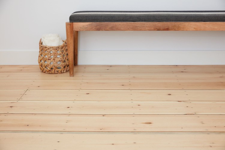 Finished floor covering with black and wooden bench next to woven basket