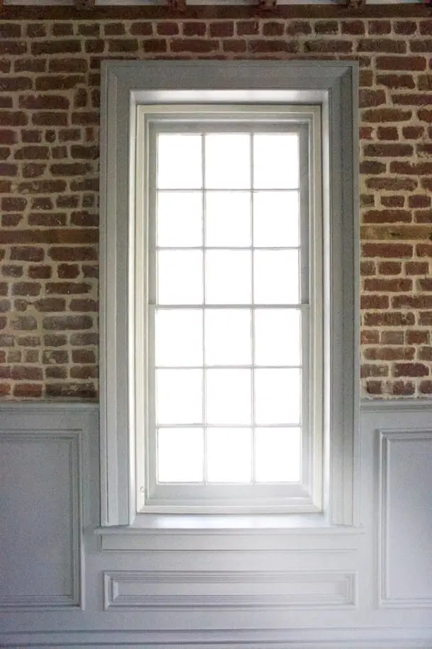 a tall window on a brick wall