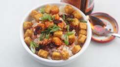 Picture of a bowl of fried with crispy tofu cubes, chili oil, and scallions.