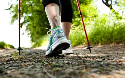 close-up of woman's ankles walking outside with hiking poles