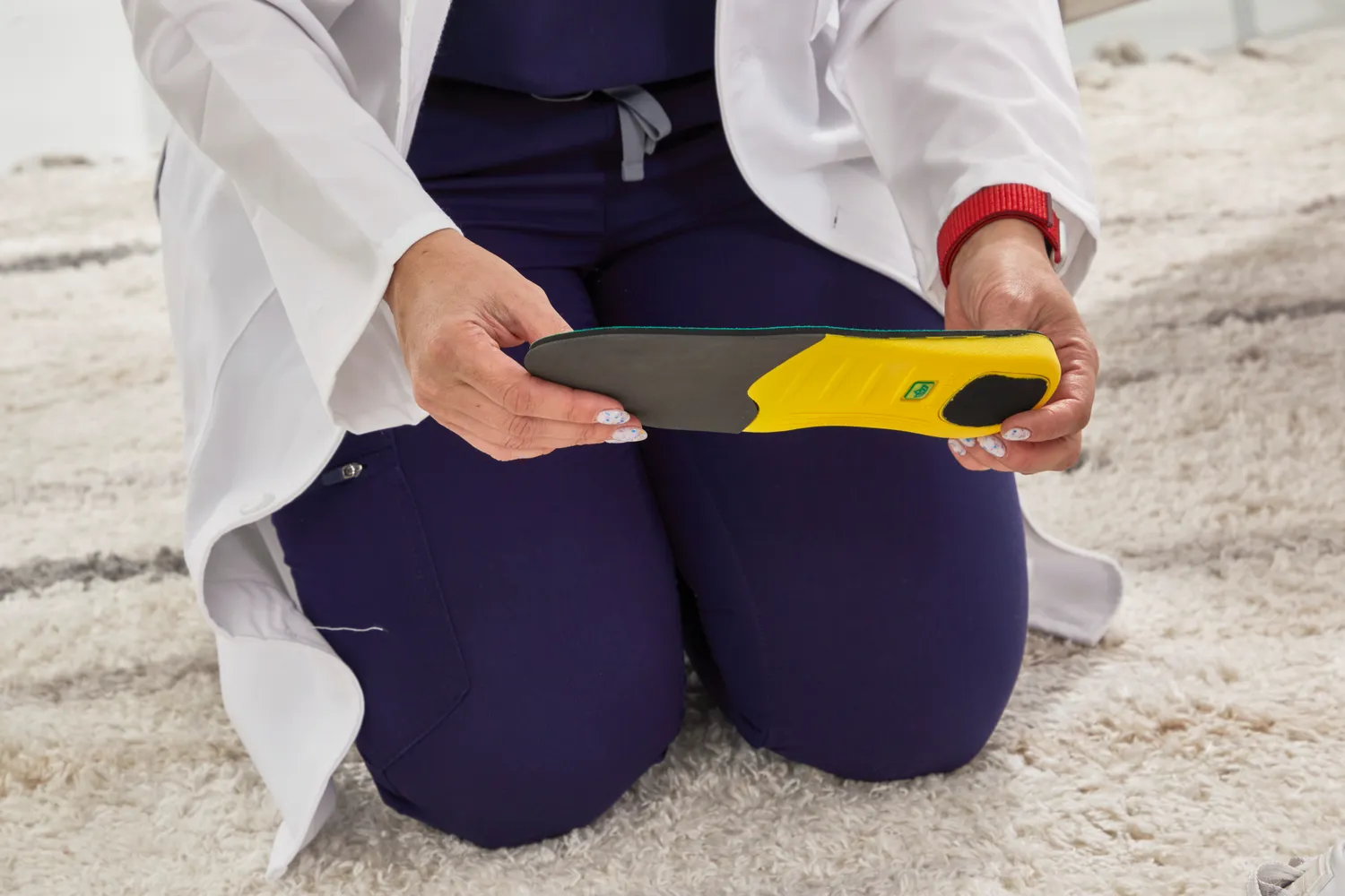 A person holding a Spenco PolySorb Cross Trainer Insole while kneeling