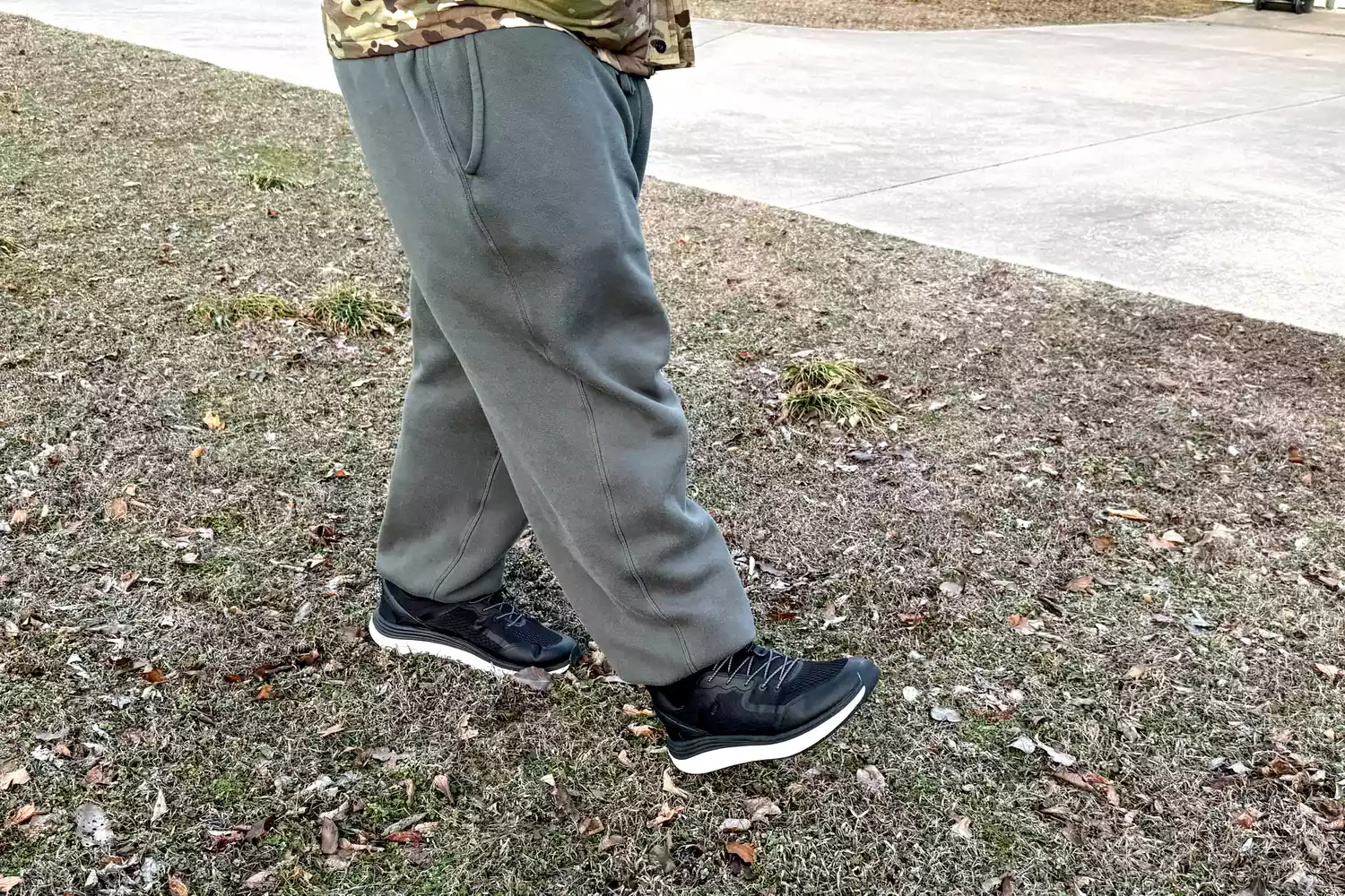 A person walking on grass while wearing the Kizik Men's London Sneakers
