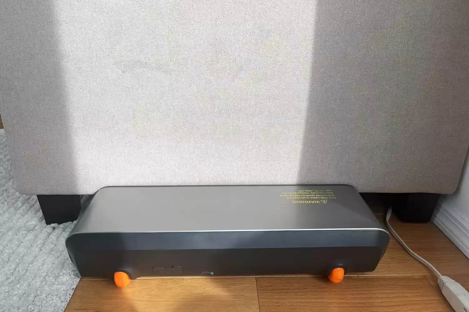 WalkingPad P1 Foldable Walking Treadmill folded and placed behind couch