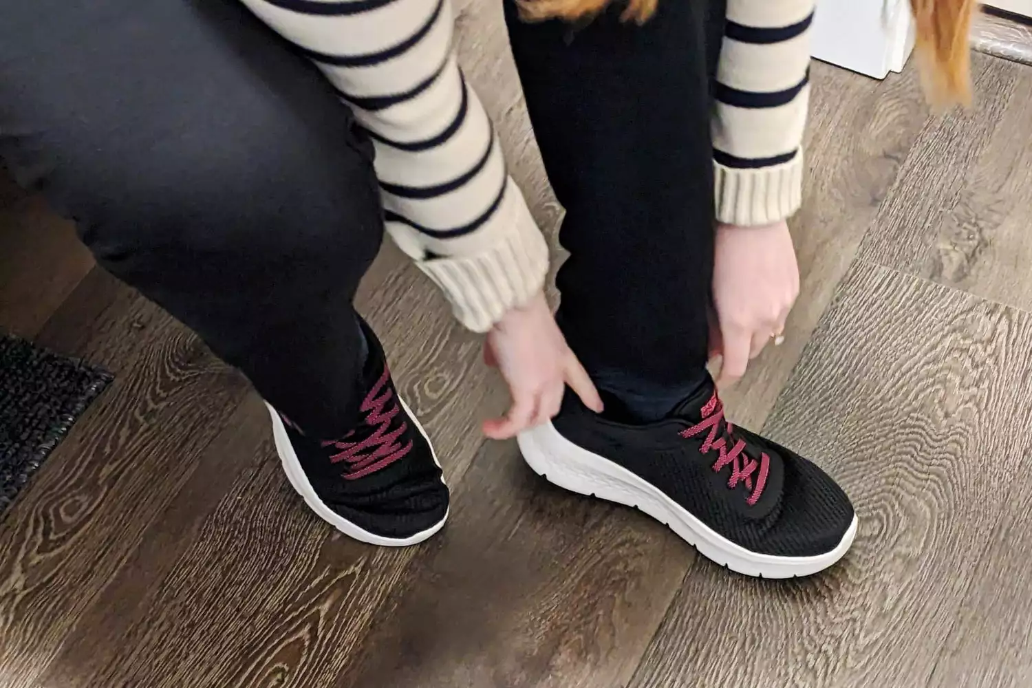 A person putting on Skechers Go Walk Flex Alani Walking Shoes while sitting