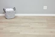 Laminate flooring installed with to white baseboard and linens basket