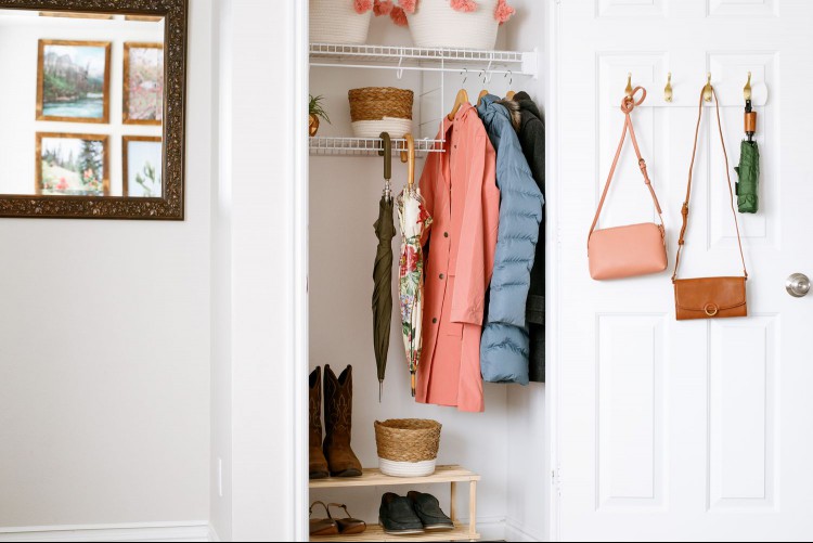 Coat closet organized with bag hooks, wire shelves and shoe bench