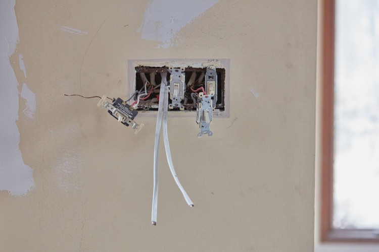Electrical outlet and wires exposed in wall of renovated house