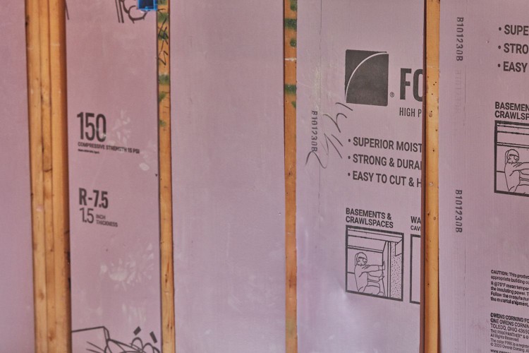 Pink insulation inserted between wooden support beams