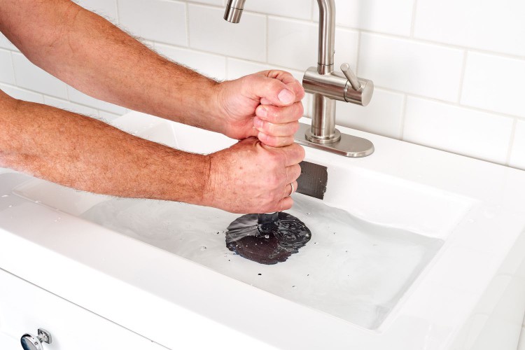 Plunger pushed up and down to clear obstruction in sink