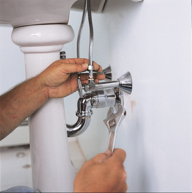 The plumbing of a pedestal sink is connected.