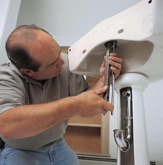 The faucet and sink of a pedestal sink are mounted.